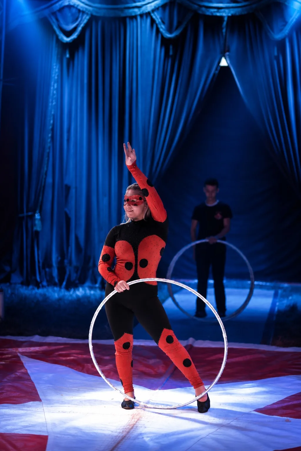 Artistin im rot-schwarzen Kostüm mit dem Cyr-Wheel in der Manege