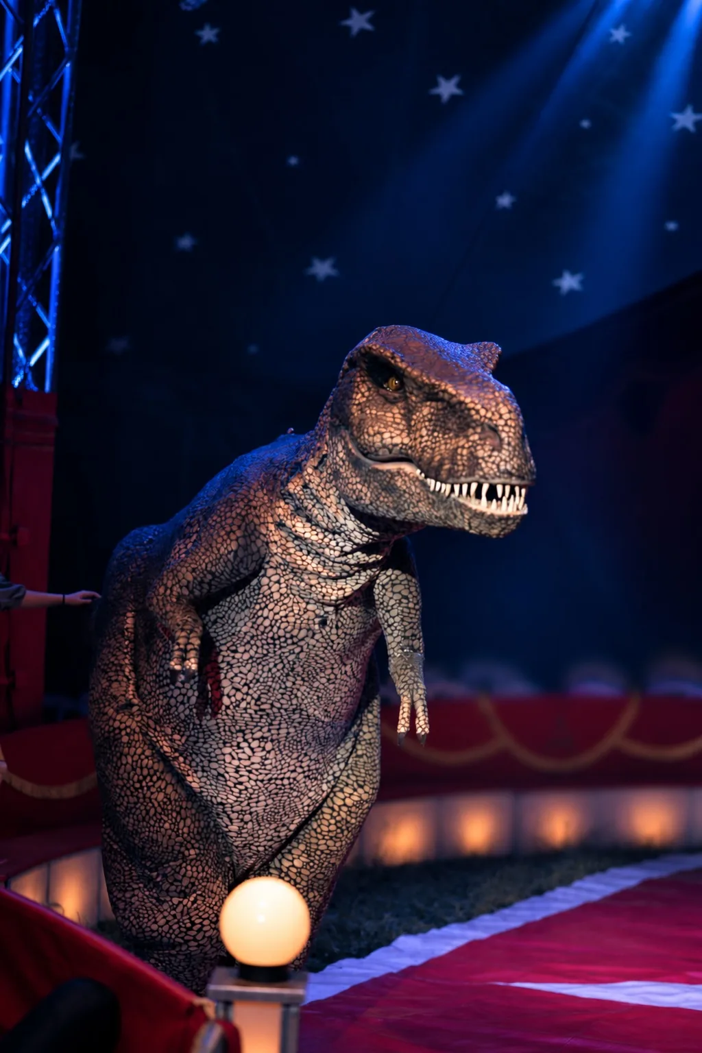 Große Dinosaurierfigur im Scheinwerferlicht der Manege